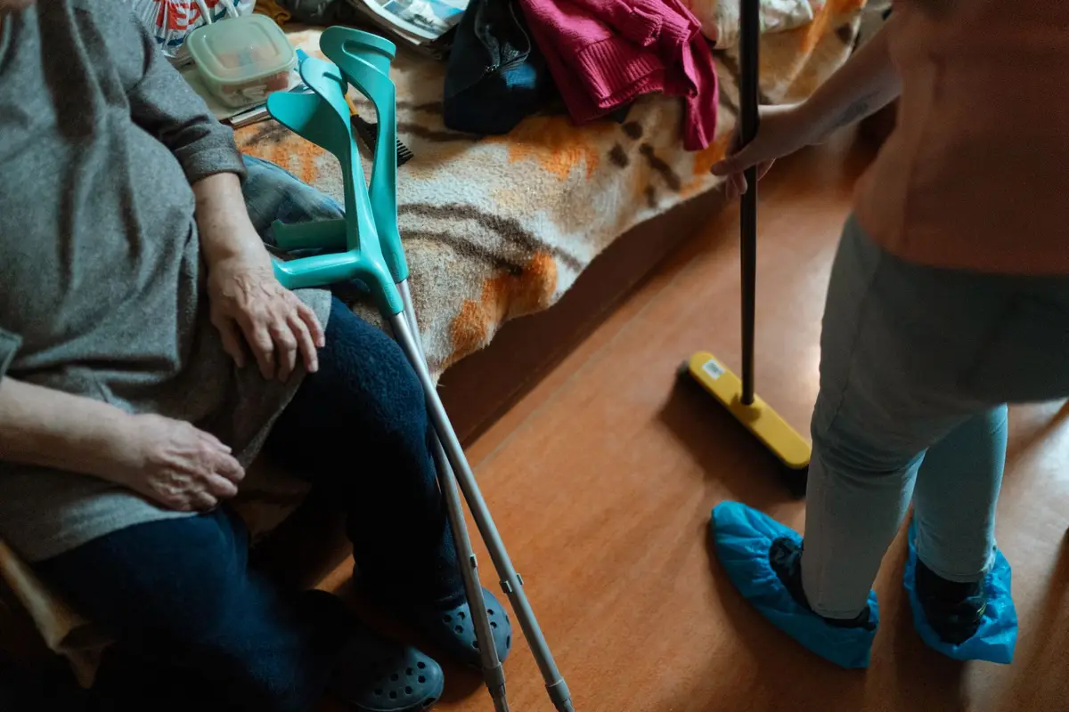 Care worker visiting an elderly client at home, reviewing notes on a tablet