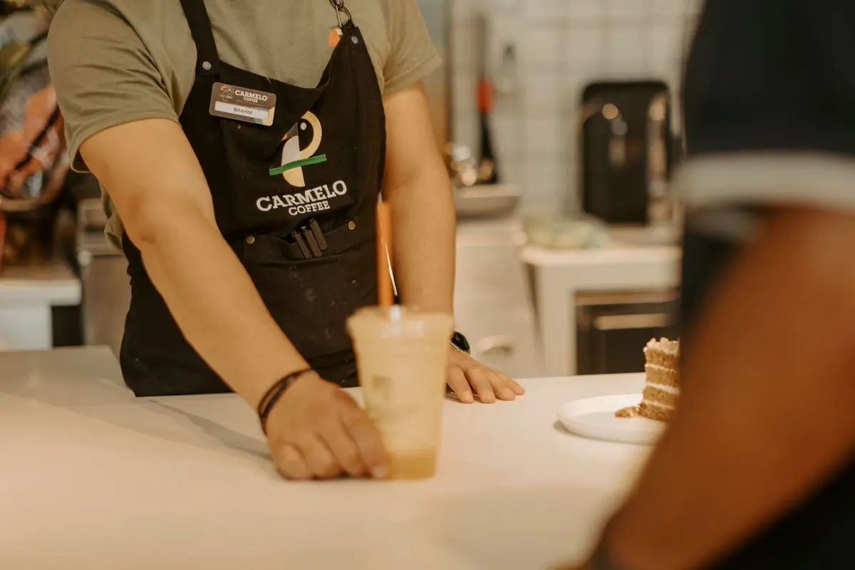 A busy coffee franchise kiosk serving customers inside a modern UK shopping centre