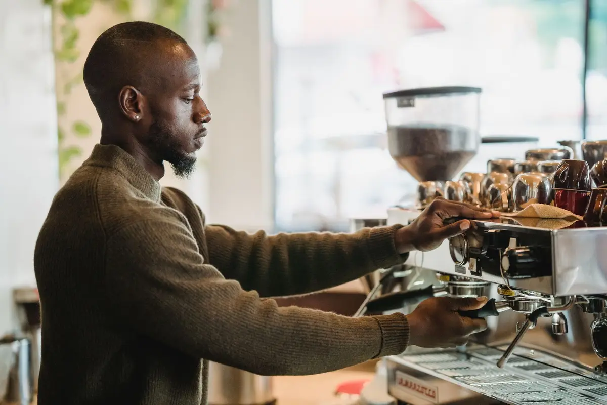 A barista preparing an espresso drink at a coffee franchise, with professional equipment on the counter