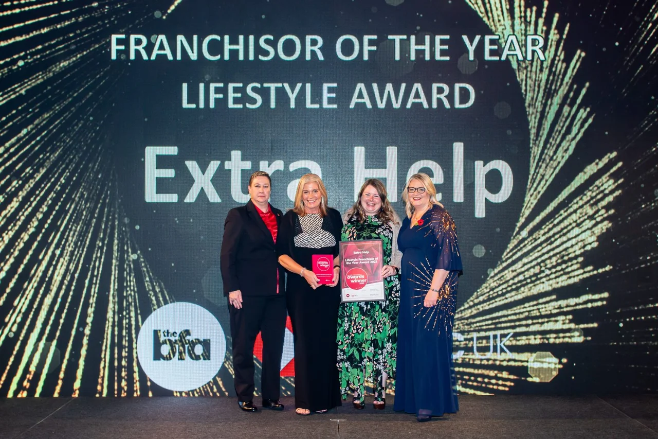 Extra Help founder Claire Robinson and her team on stage at the British Franchise Association awards, holding the 'Franchisor of the Year Lifestyle Award' plaque as Extra Help is announced the winner