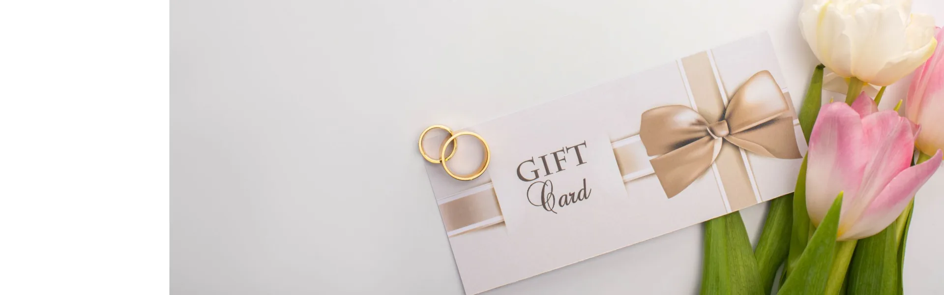 Elegant wedding gift card with gold rings and pink tulips on a light background, representing event and wedding planning franchise opportunities in the UK.