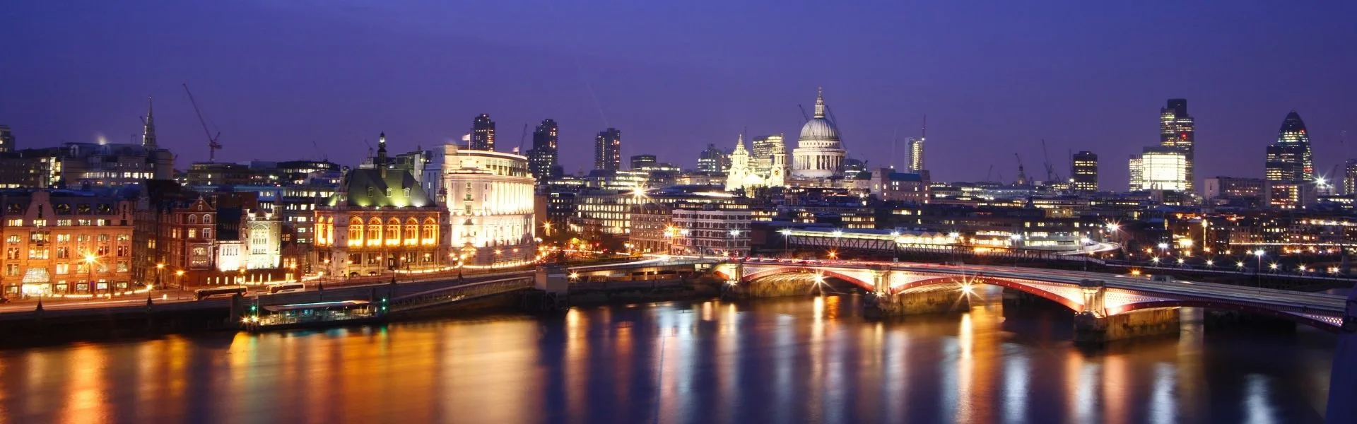 London skyline at night with St Paul's Cathedral, the River Thames and Blackfriars Bridge illuminated, representing franchise opportunities in England.